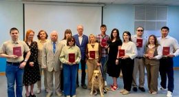 Тифлокомментарий к 3 фотографии: Общее фото выпускников программы «Менеджмент в социальной сфере» с сотрудниками аппарата управления ВОС и Института «Реакомп». В руках выпускников дипломы красного цвета, в центре, у ног слушателей, собака-проводник.