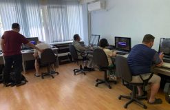 Тифлокомментарий к фотографии: компьютерный класс Института «Реакомп»: за компьютерами занимаются обучающиеся — участники специальной военной операции, рядом с ними — преподаватель института В. В. Гладышев.